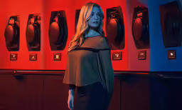 a woman in black posing in front of red light
