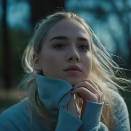 a young blonde woman posing in a park