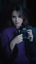 a woman holding a camera with both hands