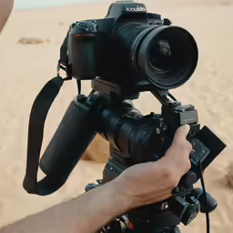 someone using a canon c7 camera on a beach