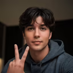 a male in a gray shirt making the sign of victory