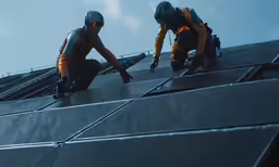 a pair of workers are installing pipes on top of the building