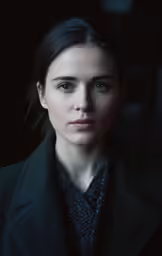 a young woman in a dark room, looking at the camera