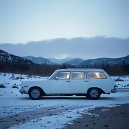 white car is parked on the side of a snowy road