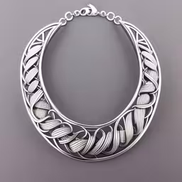 an artisanal silver necklace on display,this handmade sterling silver necklace is the ideal jewelry piece,an open bracelet on display in a silver display case,a necklace with intricate patterns on it,an artistically designed necklace on a gray background