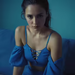 a woman with dark makeup posing on a sofa