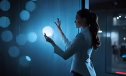 a woman looking at a glowing light fixture in a dark room