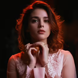 the woman is wearing a lace blouse and has her hand to her face