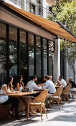 people eating outside at outdoor cafe tables on sidewalk