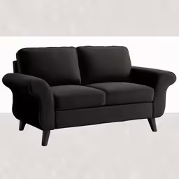 a black two seater sofa on an off - white wall