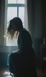 a woman sitting in front of a window on a chair
