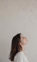 a woman is looking up and there is a wall behind her