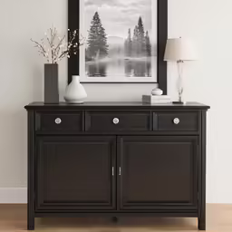an elegant black buffet or server cabinet with an ornate glass vase and a landscape in a frame