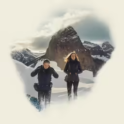 two people standing in the snow on top of a mountain