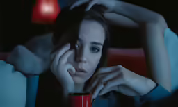 a beautiful woman sitting down with her hand on her face