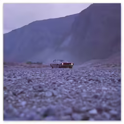 a car is shown parked on rocks near mountains