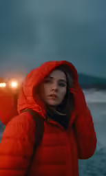 woman in an orange coat is on the beach