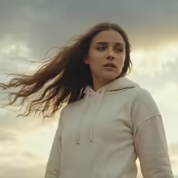 a woman standing in front of a cloudy sky