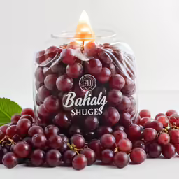 grapes in the water and on top of it, surrounded by a candle