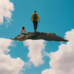 man on rock looking into sky from atop