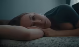 a woman laying on a bed wearing a black shirt