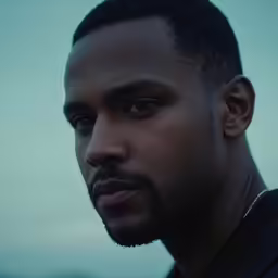 a black man with a serious face stares off to his left