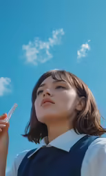 a girl in a uniform and eye glasses holds a cell phone up to the sky