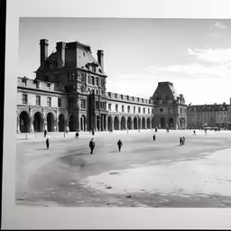 a group of people walking down a sandy beach near an old building