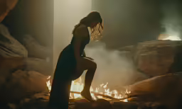 a woman in tight pants standing in front of flames