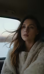 a woman in a car with her hair blowing in the wind