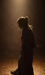 a woman sitting down in the dark looking at something