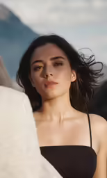 the woman wearing a black one piece is posing with her head covered