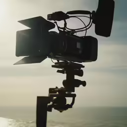 a camera attached to a large tripod by the beach