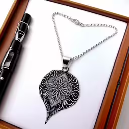 a pen in a box with a large pendant and the words on it,a pen and necklace are laying on a wooden box