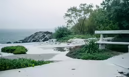 a white bench sitting on top of a sandy beach