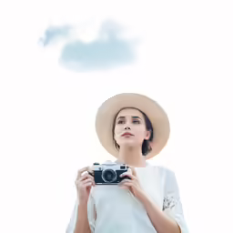 a woman is holding a camera near the ocean