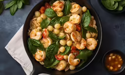 a pan filled with pasta, tomatoes, shrimp and basil
