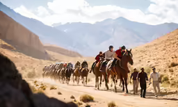 people riding horses in a mountain range with mountains