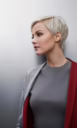 a woman with blond hair standing next to a wall