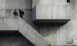 two people standing on stairs and talking at something