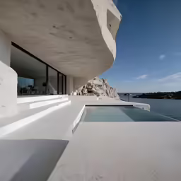 white modern house near the ocean with large windows