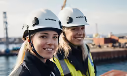 two woman in hardhats pose for the camera