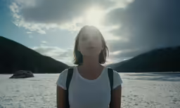 a woman with backpack in snow looking up at the sky
