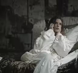 a beautiful woman in a robe laying in bed on her phone