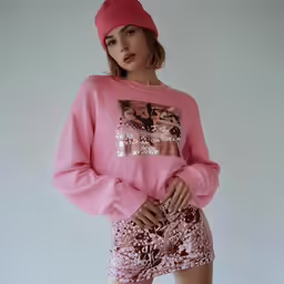 a beautiful young lady posing in shorts and a pink sweatshirt