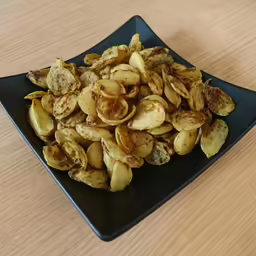 pile of fried and salted almonds in a square plate on a wooden table