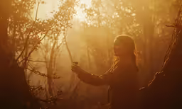 a woman standing in the woods while holding something in her hand