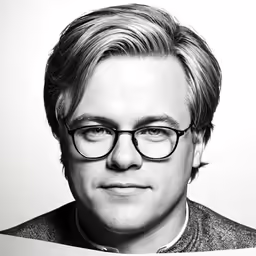 a man with glasses standing in front of a white background