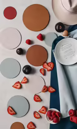 a white table with three plates and several different types of fruits on it