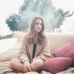 young woman sitting on the couch wearing an open cardigan